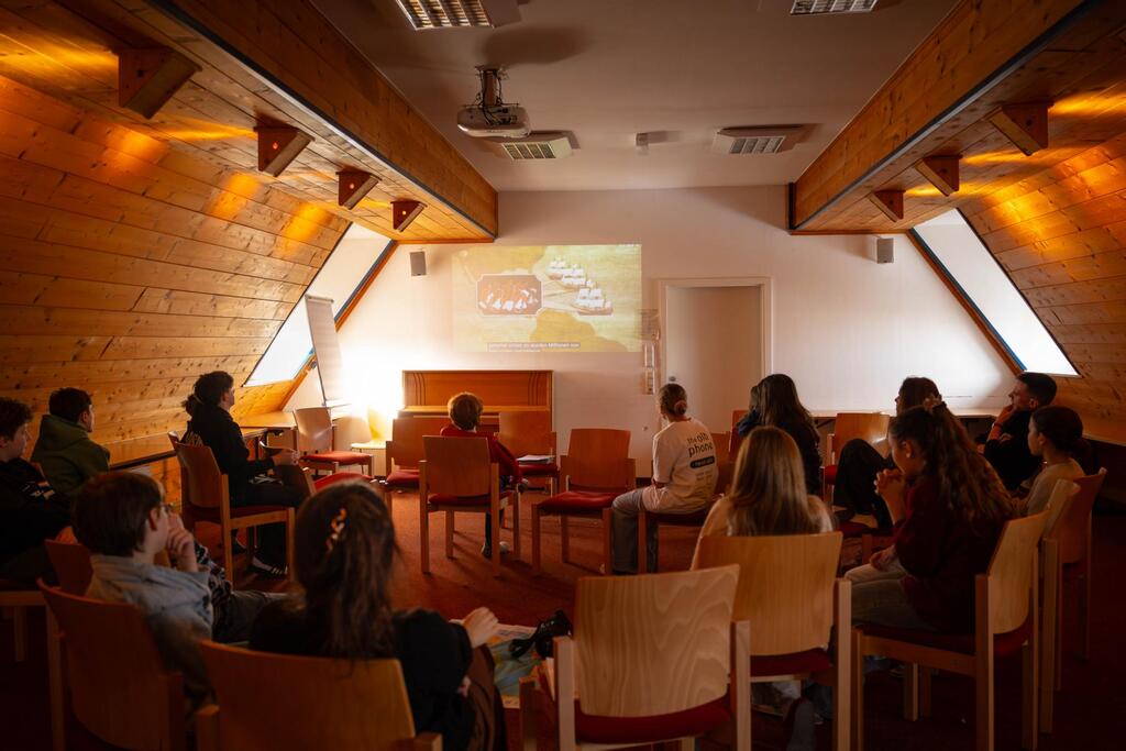 Schüler:innen schauen beim Anti-Rassismus Workshop einen Film über Kolonialismus an und spielen das Weltverteilungsspiel.
